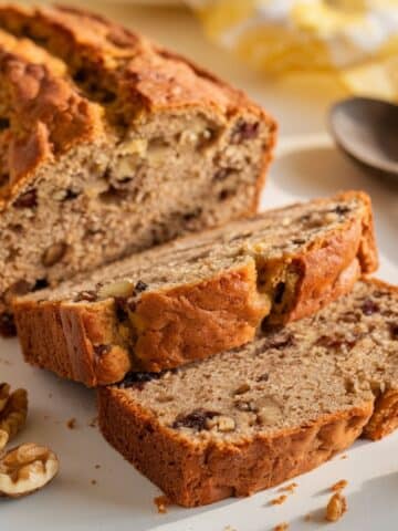 Banana bread with walnuts on a white surface.