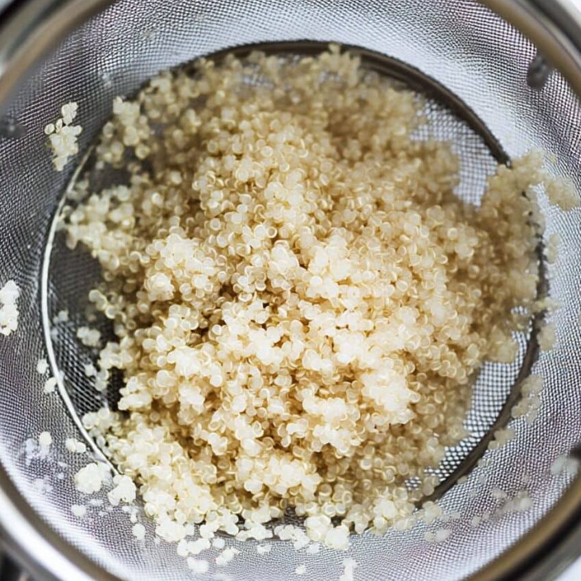 Rinsing quinoa in a fine mesh strainer over the sink