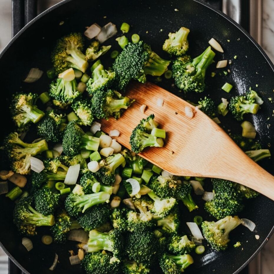 Broccoli being stir-fried in a skillet with garlic and ginger

