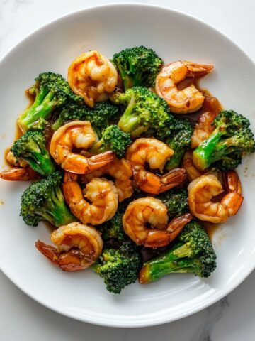 Homemade shrimp and broccoli stir fry recipe served hot on a white plate