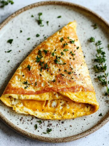 Top-down view of a fluffy omelette folded with melted cheese, served on a white marble kitchen counter