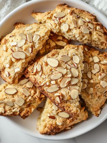 Freshly baked almond scones recipe on a white marble counter with sliced almonds on top