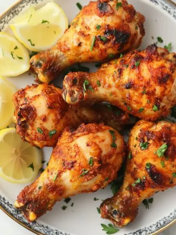 Crispy chicken drumsticks recipe on a warm plate with lemon wedges in a cozy kitchen setting.