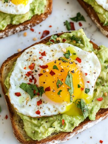 Homemade avocado toast with poached egg recipe on a white marble kitchen counter