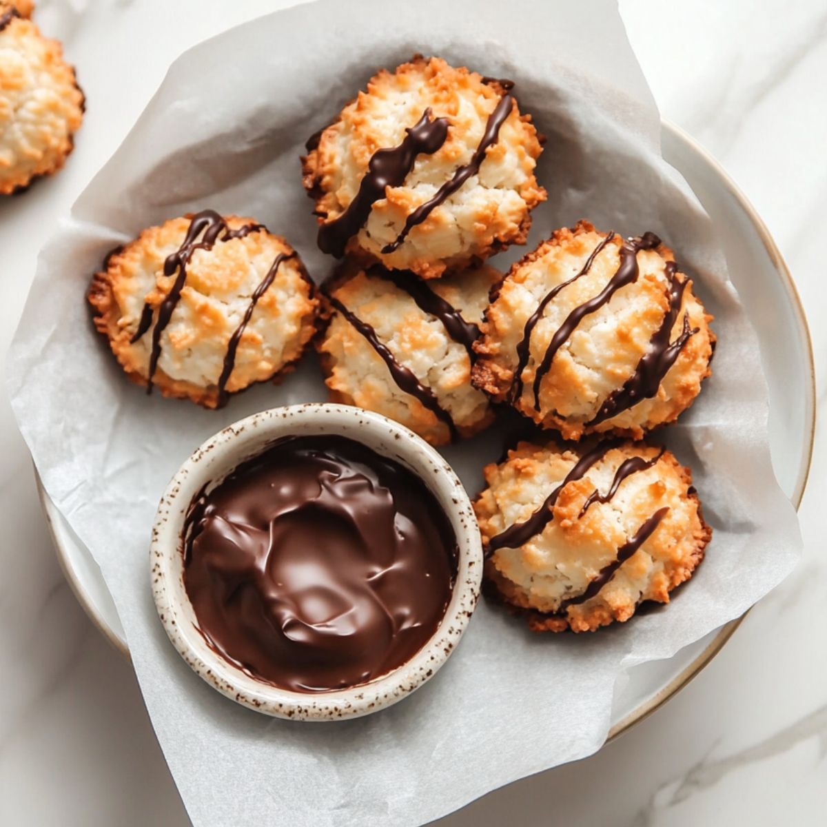 Freshly baked coconut macaroons recipe on a tray, some dipped in chocolate, with a golden and rustic homemade look