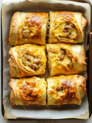 Freshly baked sausage, egg, and cheese breakfast roll ups on a white marble counter