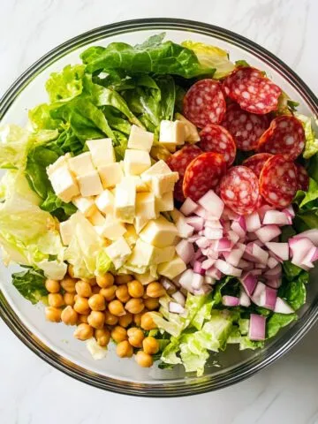 Top-down view of La Scala chopped salad recipe served in a glass bowl on a white marble counter