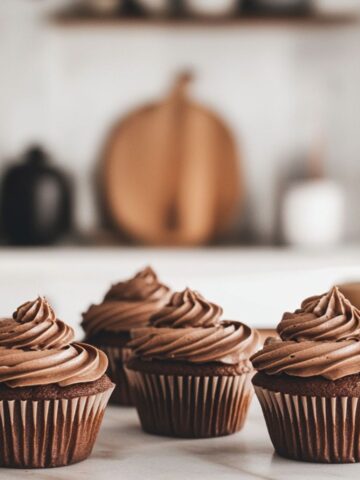 Homemade chocolate cupcakes with chocolate frosting on a clean white marble counter