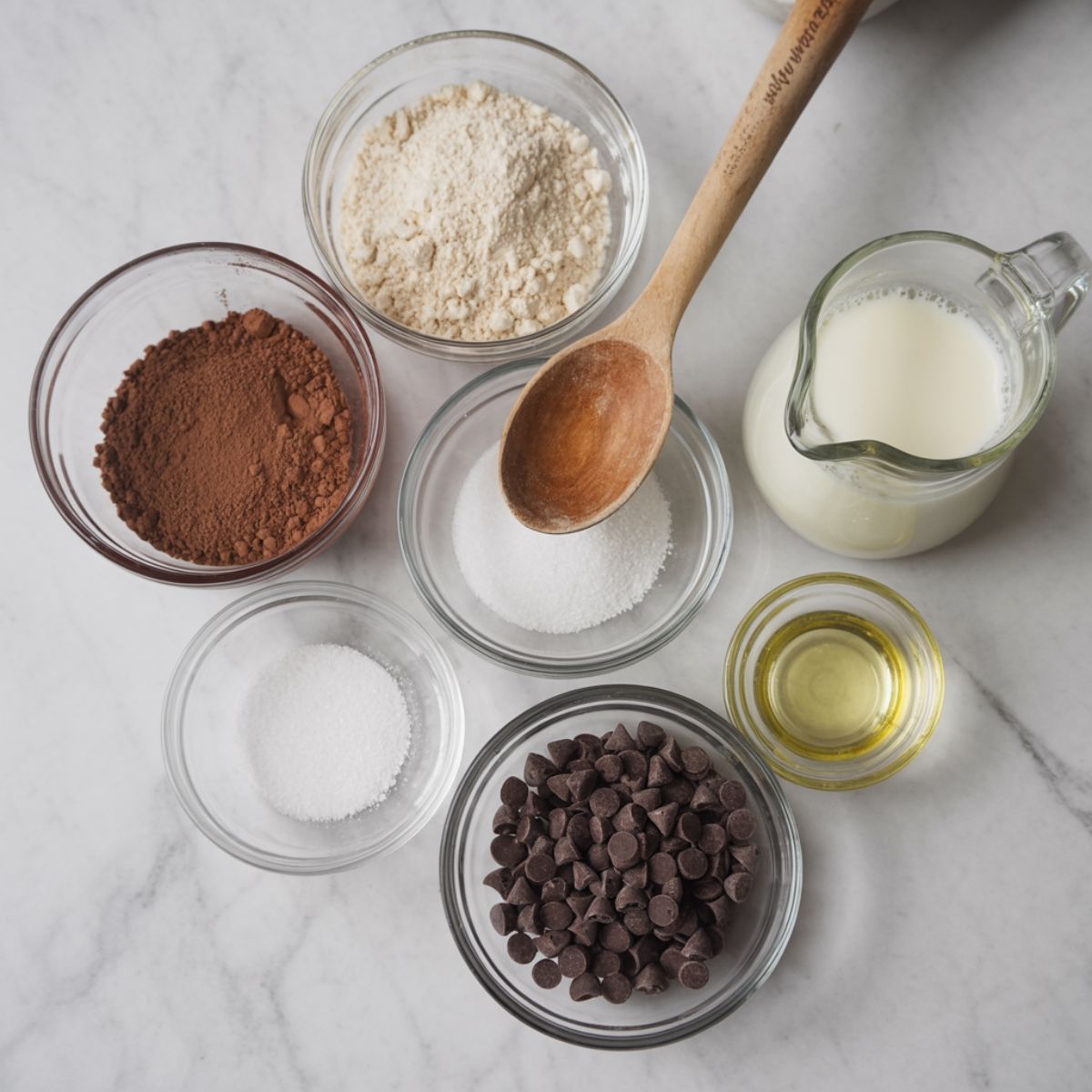 All the ingredients for a mug cake recipe arranged in glass bowls on a marble countertop
