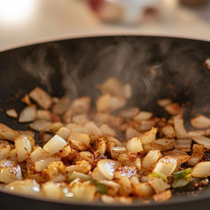 Creating curry base with onions, garlic, and spices.