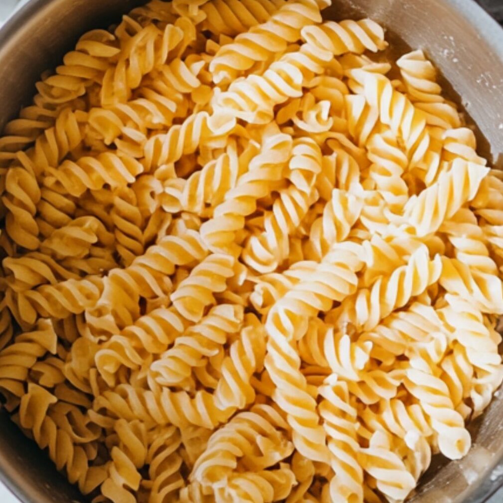 Pasta boiling in pot with vegetables prepped on the side
