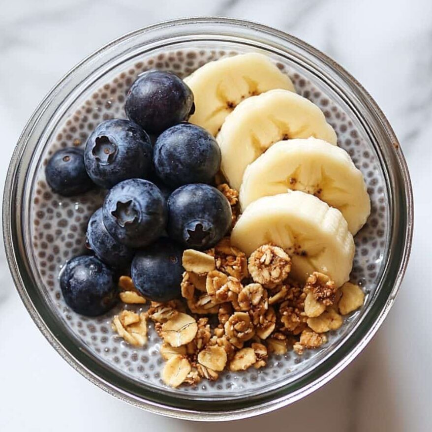 Chia pudding served with strawberries and nut butter on a marble kitchen counter