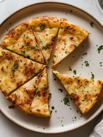 Final Tortilla Española recipe sliced into wedges on a plate with a homemade, rustic appearance.