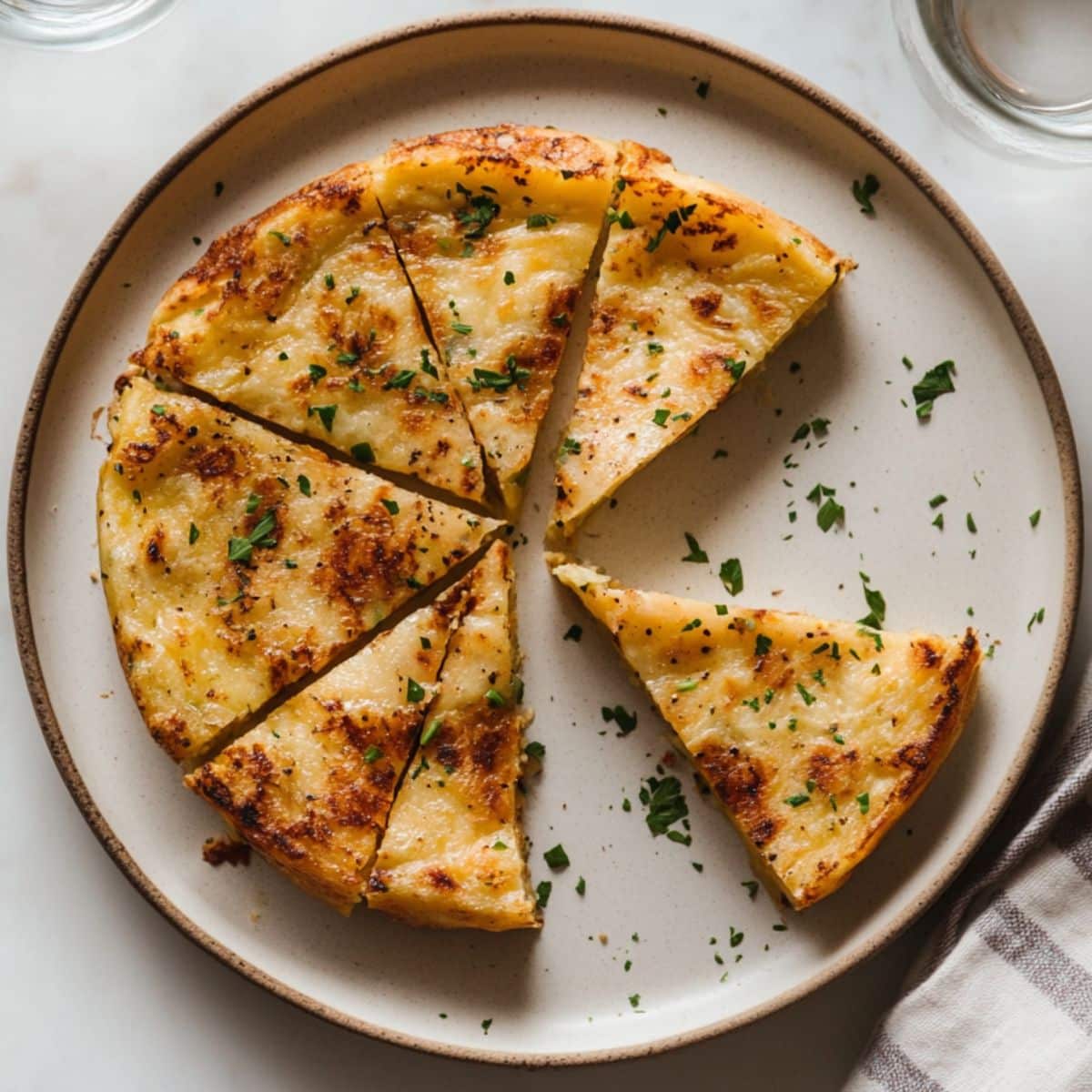 Final Tortilla Española recipe sliced into wedges on a plate with a homemade, rustic appearance.