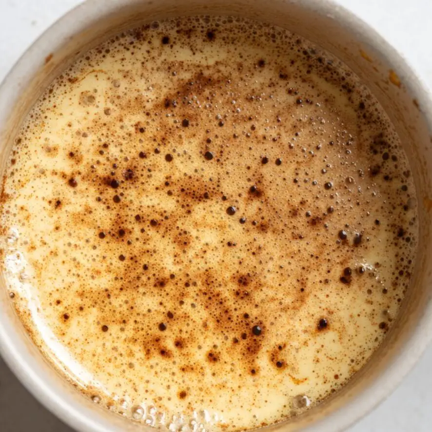 Light saucepan with browned butter showing brown specks at the bottom

