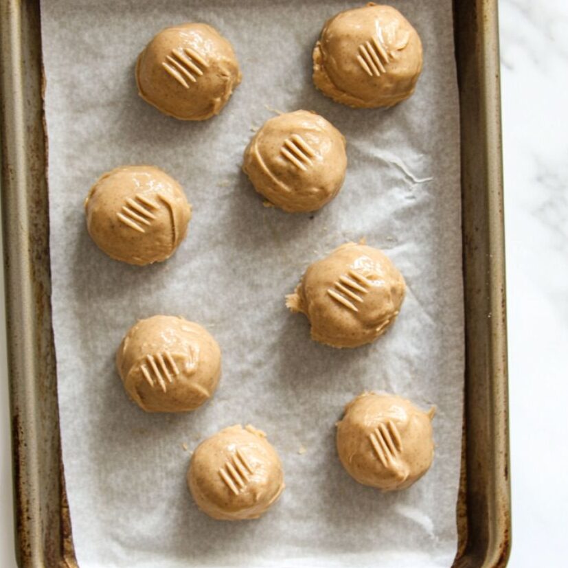 Peanut butter cookie dough balls with fork marks on parchment paper