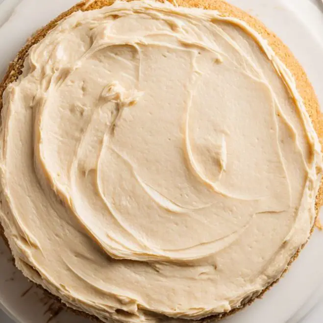 Frosting banana cake with caramel buttercream on white marble counter