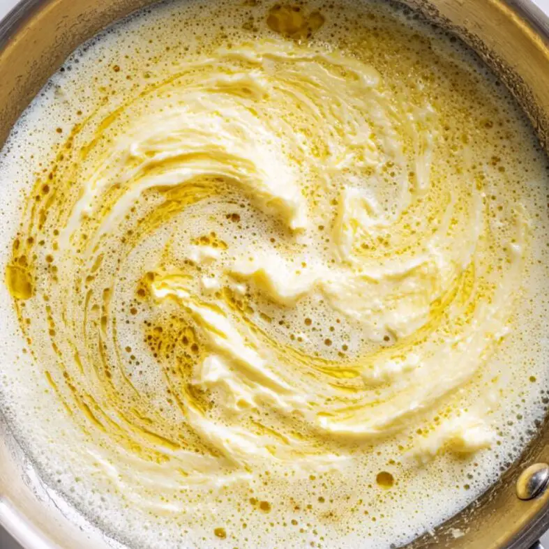 Butter, cream, and garlic simmering in a stainless steel pan

