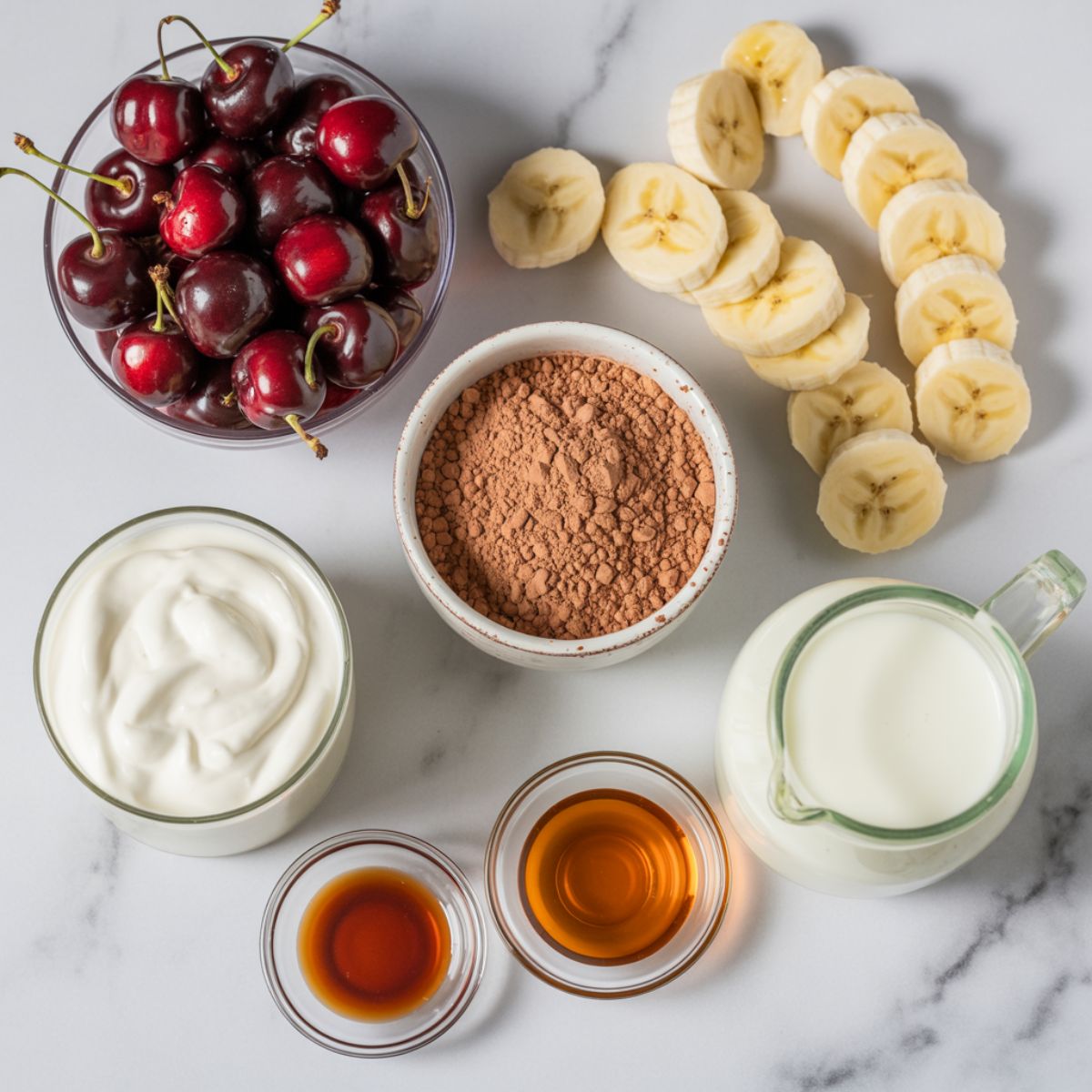 Flat lay of all ingredients for a chocolate cherry smoothie recipe  on marble counter.