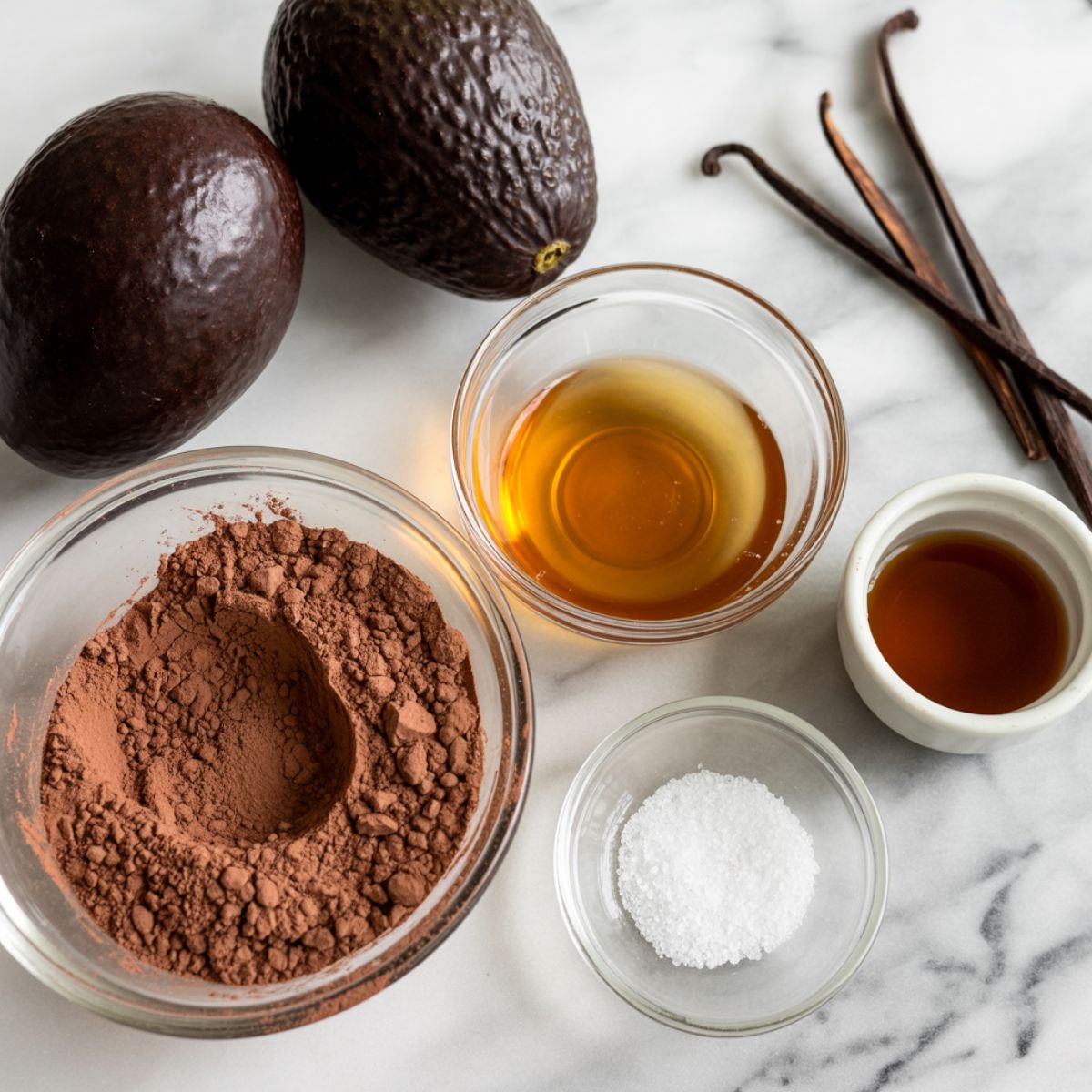 Ingredients for dark chocolate avocado mousse recipe laid out on a white marble countertop