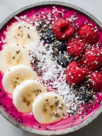 A vibrant dragon fruit smoothie bowl recipe with fresh toppings on a white marble countertop