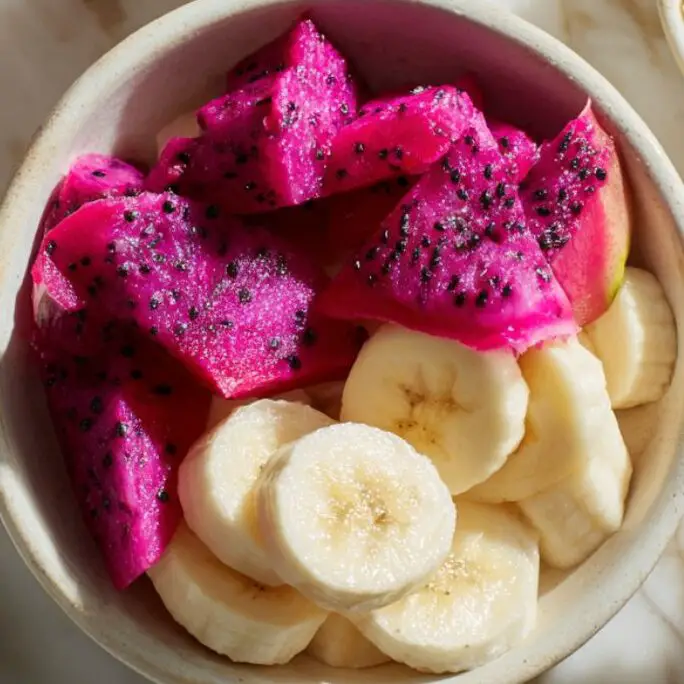 Prepped smoothie ingredients including sliced banana and dragon fruit on white countertop
