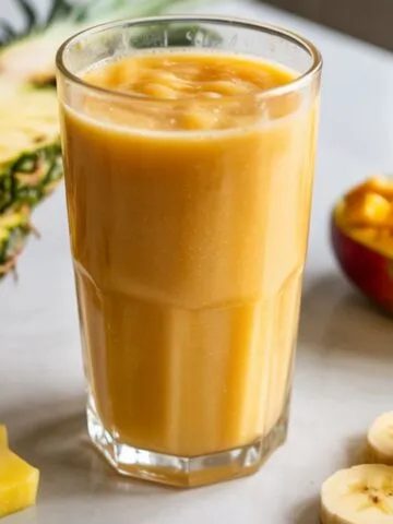 Glass of homemade tropical smoothie recipe on a white kitchen counter