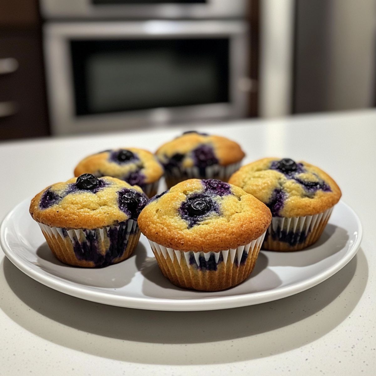 Fresh homemade blueberry muffins recipe cooling on a rack on a white marble counter
