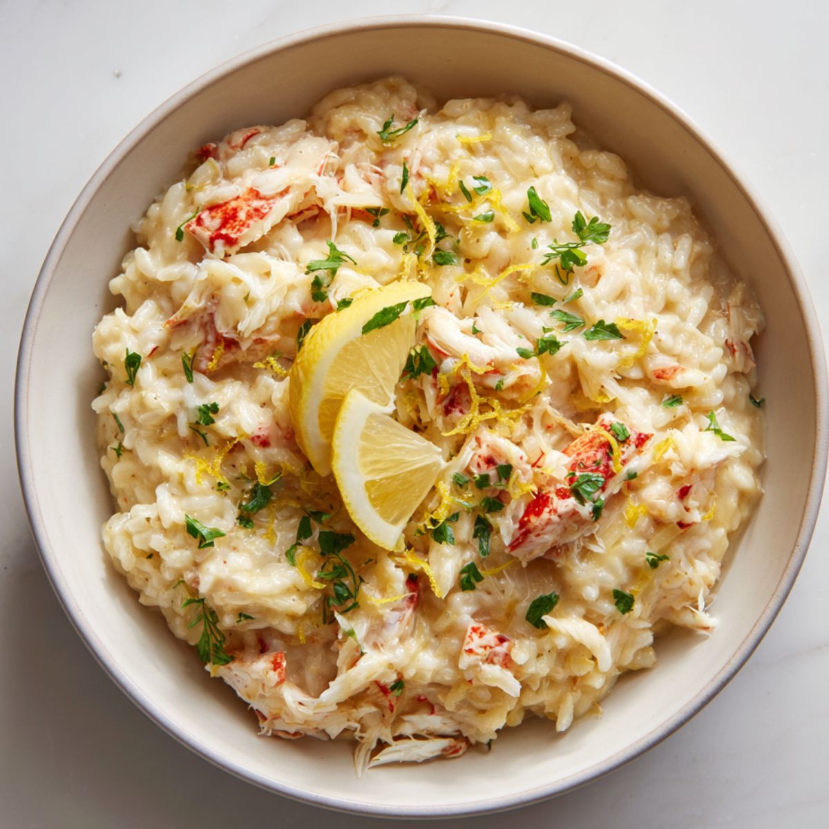 Creamy crab risotto recipe served in a white bowl with lemon zest