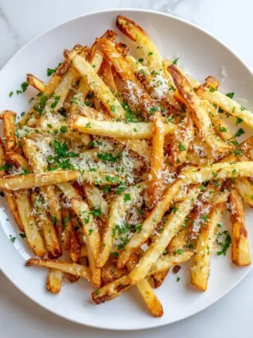 Golden brown garlic parmesan fries recipe served on a white plate with cheese and parsley