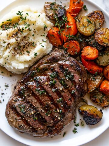 Garlic butter steak recipe with mashed potatoes and veggies on white plate