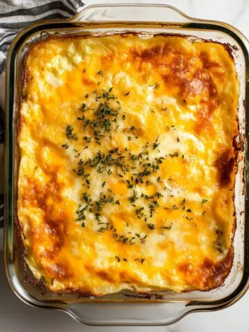 Golden baked hashbrown egg casserole recipe in a glass dish on a white marble kitchen counter