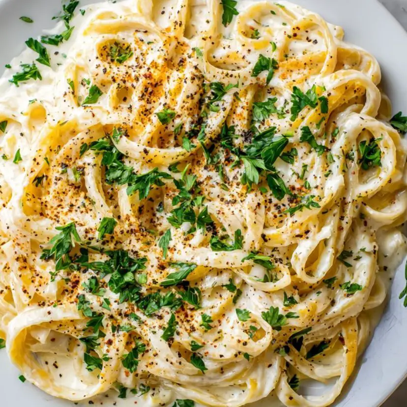 Freshly made Fettuccine Alfredo garnished with parsley and pepper

