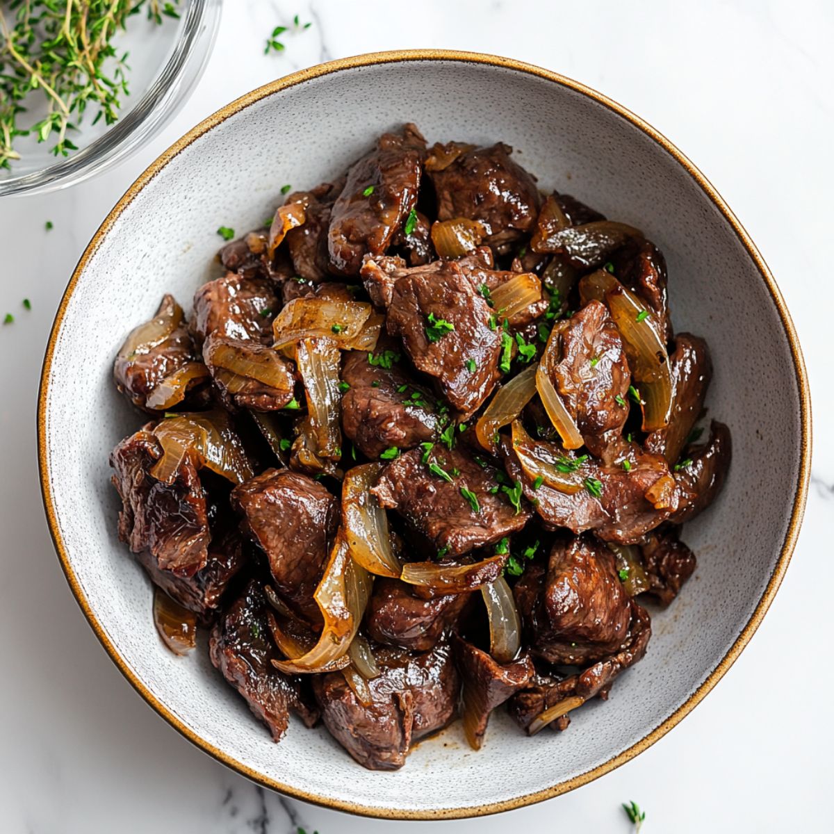 Classic liver and onions recipe in a cast-iron skillet with golden caramelized onions on a white marble countertop