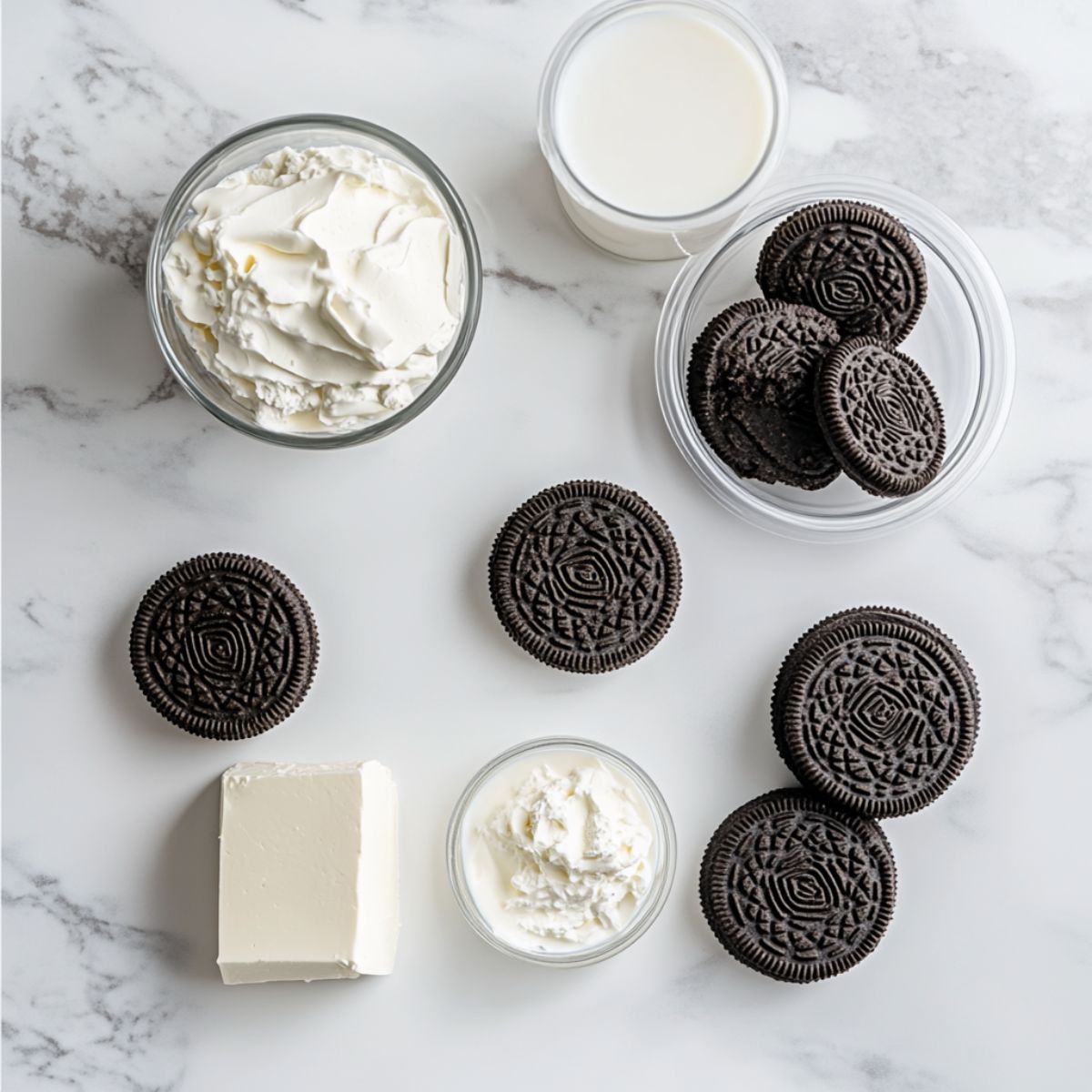 Oreo pudding recipe ingredients on a white counter including Oreos, Cool Whip, pudding mix, milk, and cream cheese.