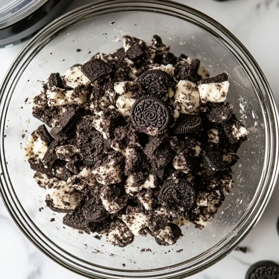 Crushed Oreos in a glass bowl with visible chunky and fine pieces.