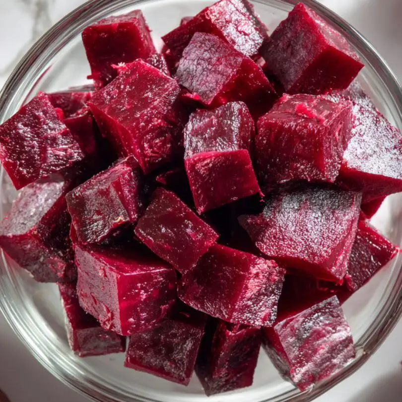 Cubed beetroot in a glass bowl with peels and beet stains around