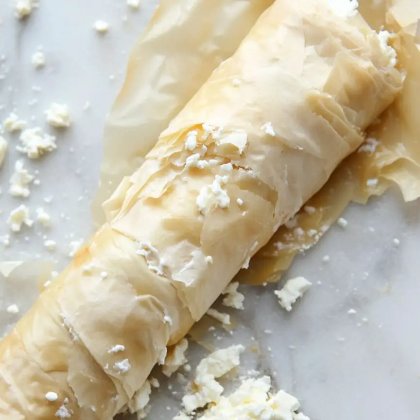 Phyllo strip filled with cheese being rolled into borek shape