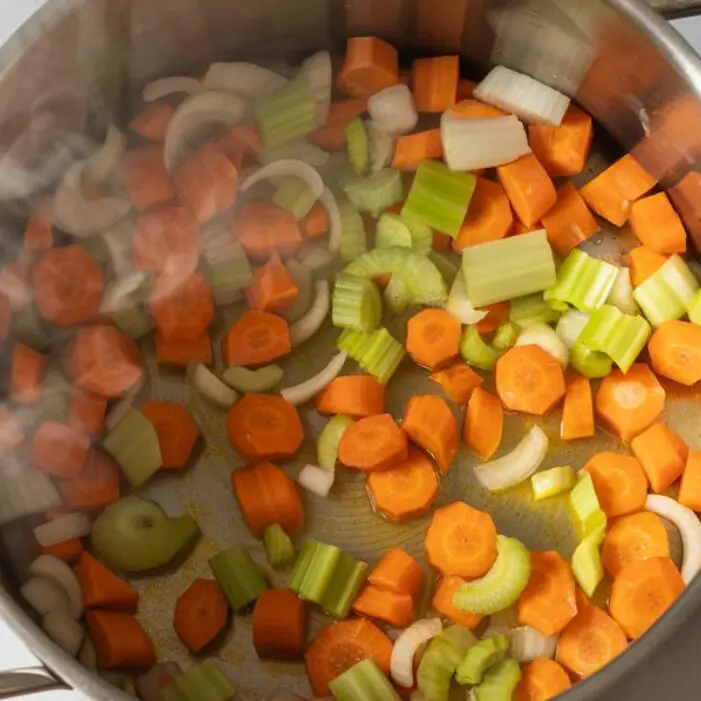 Carrots, celery, and onion sautéing in a glass pot to start the soup