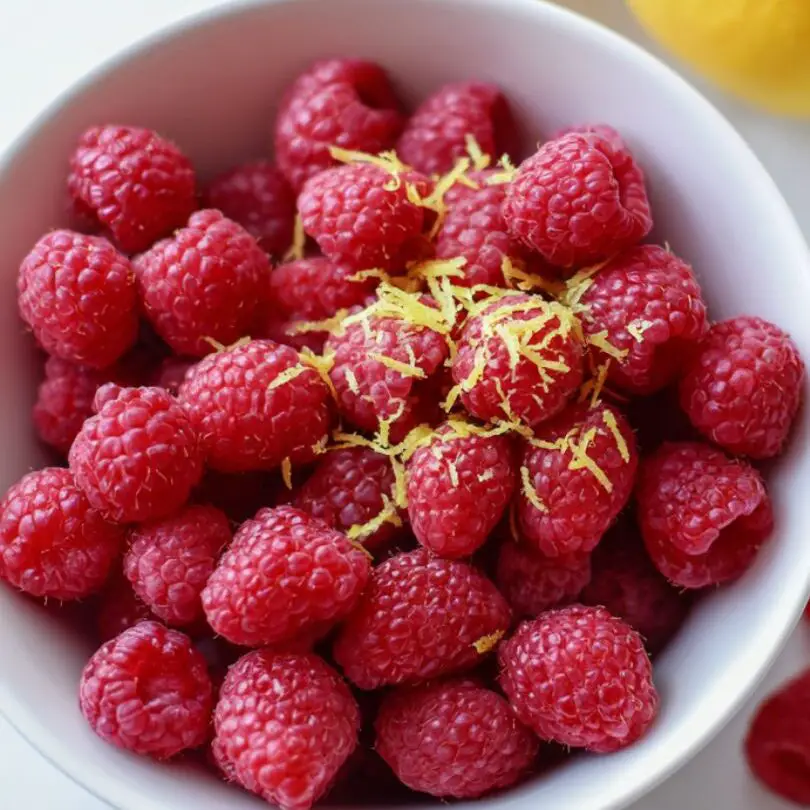 Fresh raspberries and lemon zest prepped on white counter
