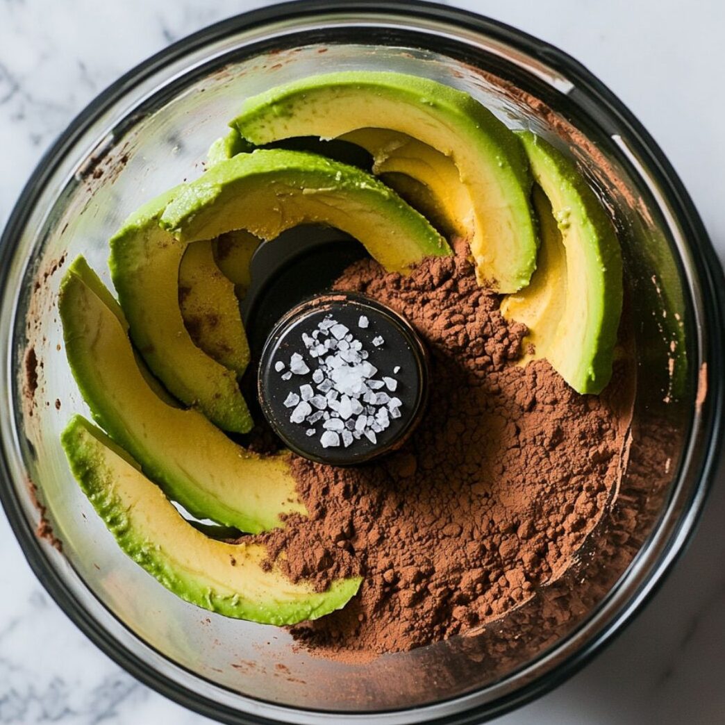 Avocado and cocoa in a food processor bowl ready to blend