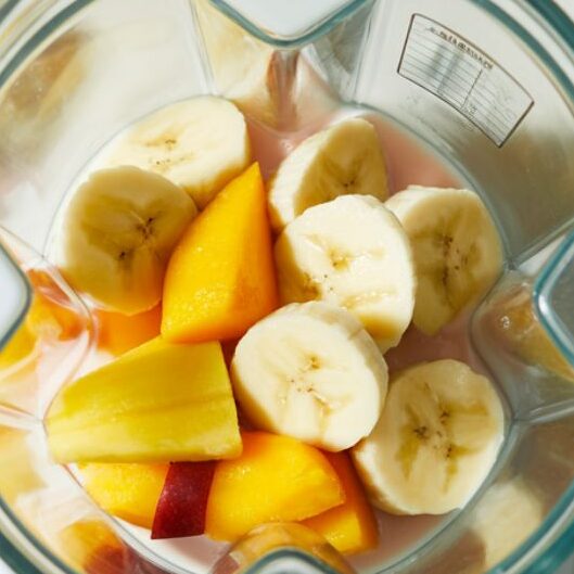 Tropical fruits and coconut milk layered in a blender