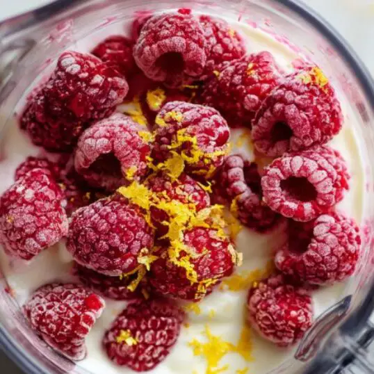 Raspberry lemonade smoothie ingredients in a blender, unblended