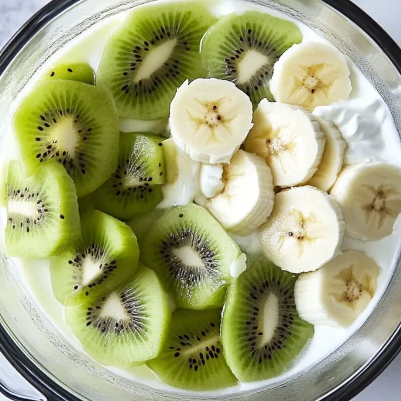 Blender filled with kiwi, banana, yogurt, and milk