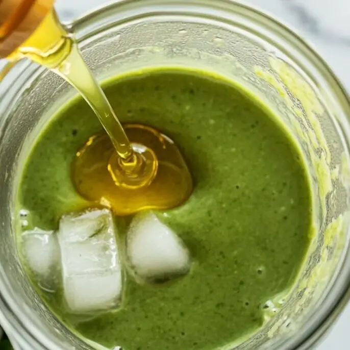 Honey and ice next to smoothie mixture in blender