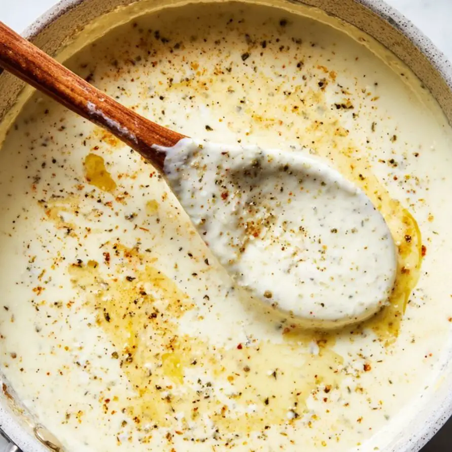 Alfredo sauce simmering with melted Parmesan in a skillet