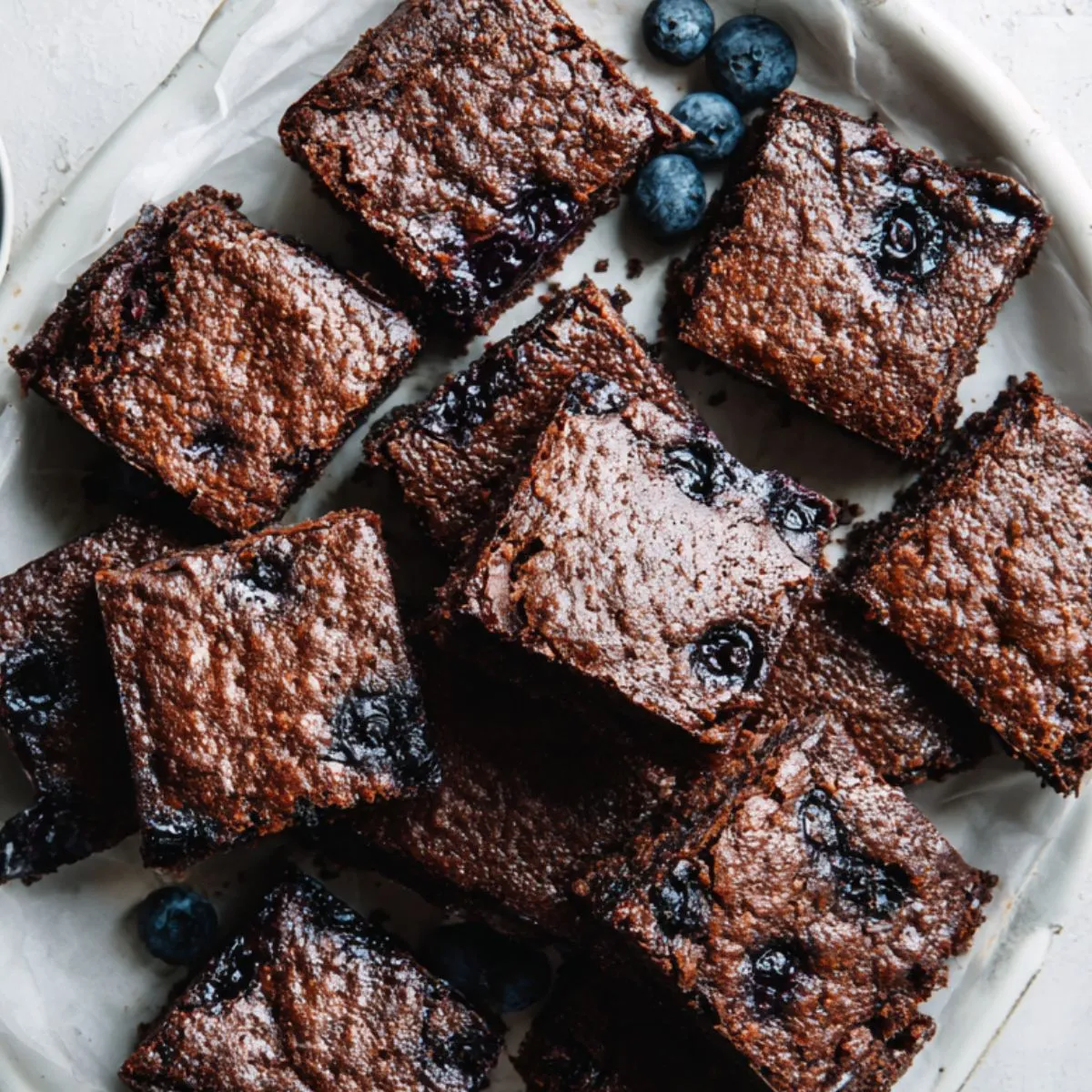 Homemade blueberry brownies recipe cut into squares on parchment paper

