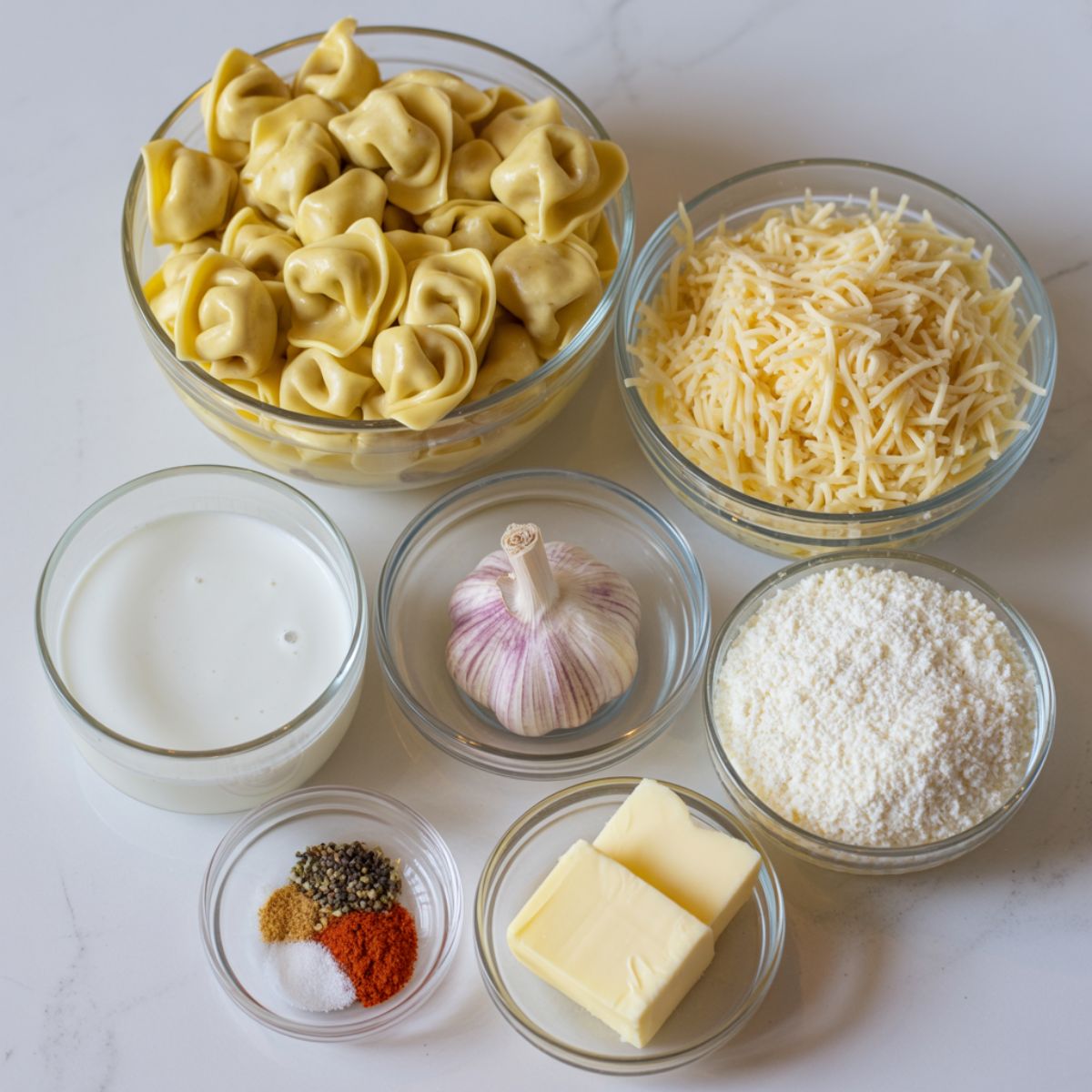 Ingredients laid out for making Tortellini Alfredo Bake on a white countertop.