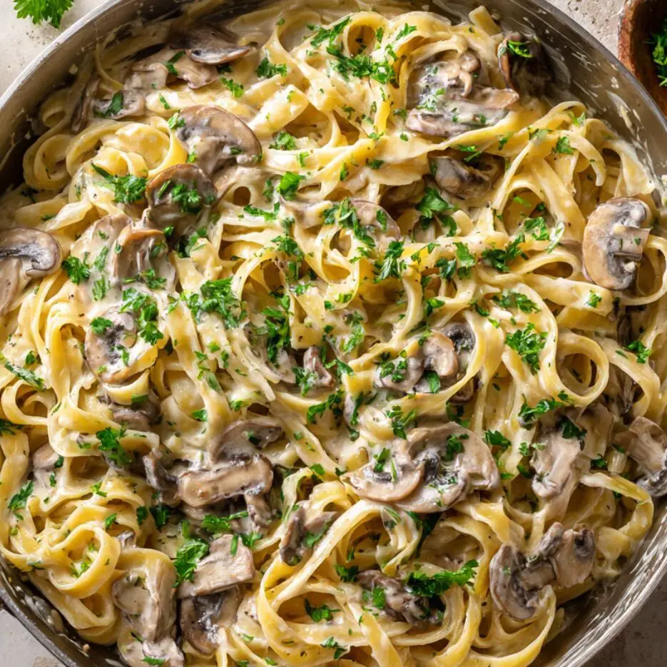 Fettuccine pasta tossed with creamy mushroom Alfredo sauce in a pan