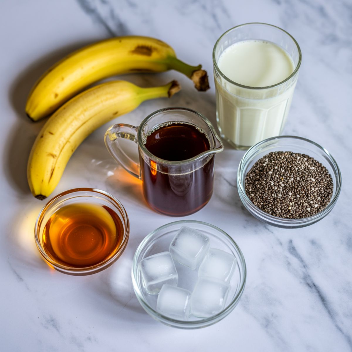 Ripe bananas, brewed coffee, milk, and other ingredients laid out for a banana coffee smoothie

